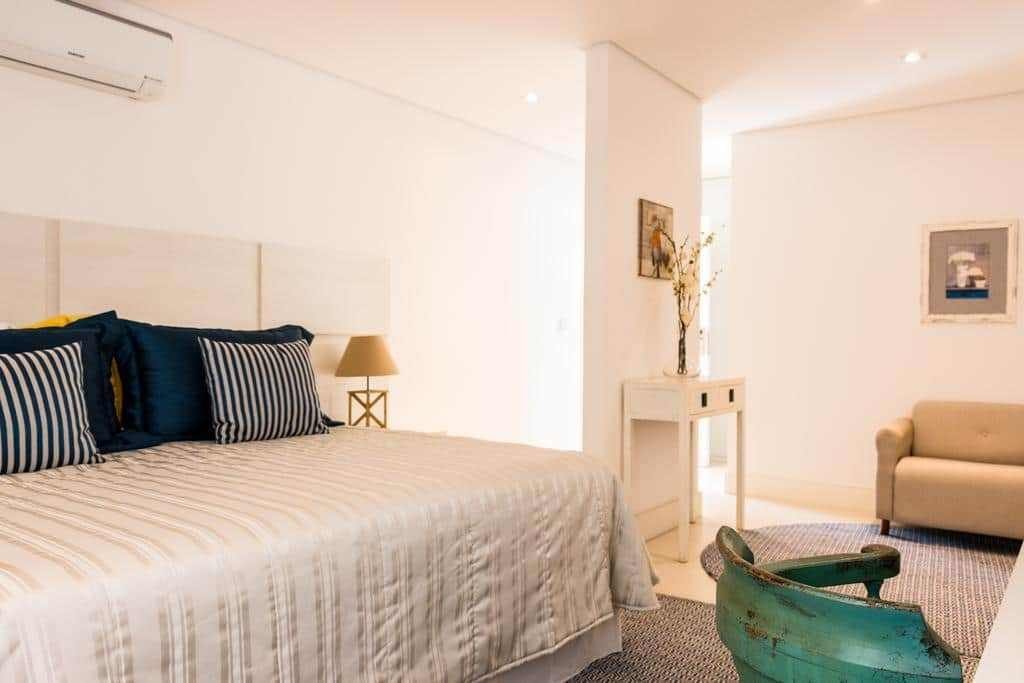 Um dos quartos do Hotel Maui Maresias com cama, cadeira, estofado, criado mudo e ar condicionado Hotéis e resorts para férias