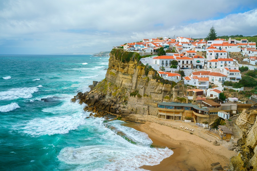 Vista das casas em cima do morro e do mar azul ao lado em Portugal