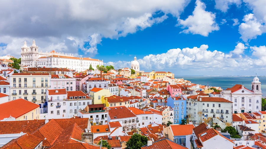 Vista aérea da cidade de Lisboa com casas coloridas, mar ao fundo e céu azul O que fazer em Lisboa