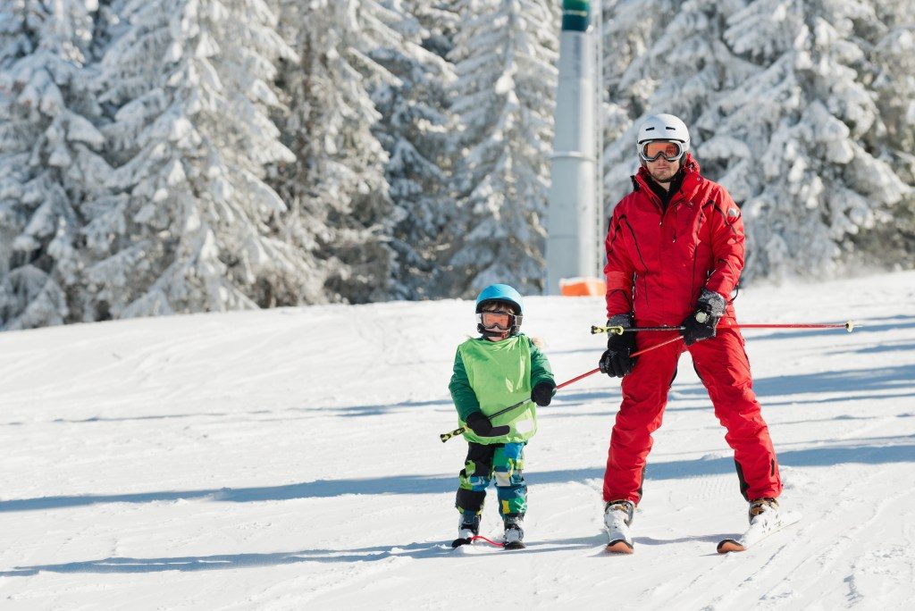 Criança e adulto praticando esporte na neve Contratar seguro viagem para férias