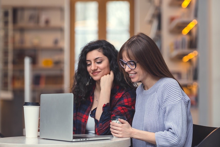 Duas mulheres olhando o notebook em cima de uma mesa Como reservar hotéis pela intenet
